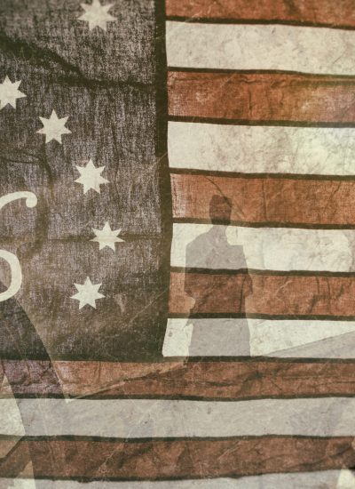 Distressed American flag with the number 76, colonial-era soldiers, and a liberty bell symbolizing the Revolutionary War and America250 celebrations.