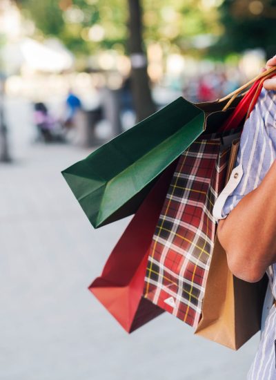 A smiling shopper carries colorful shopping bags