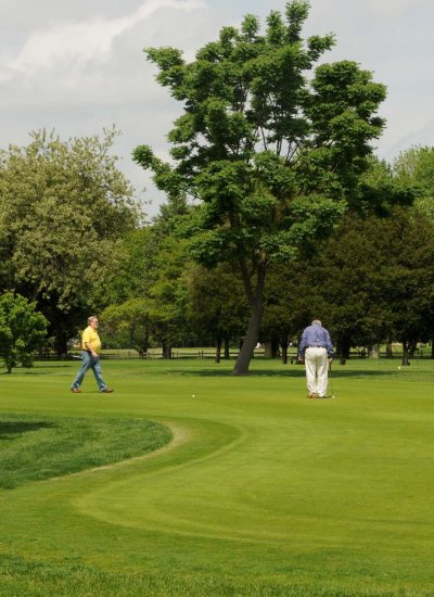 Golfers playing on a scenic Eisenhower Park surrounded by lush fairways, mature trees, and landscaped greens.