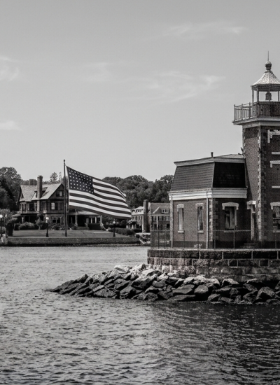 Stepping Stones Lighthouse in Long Island Sound off Kings Point, Nassau County, with the North Shore shoreline and historic homes in the background.