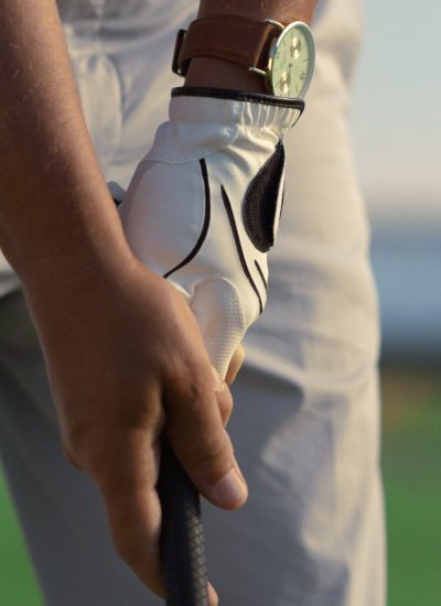 Close-up of a golfer gripping a golf club while preparing for a shot on a sunny day.