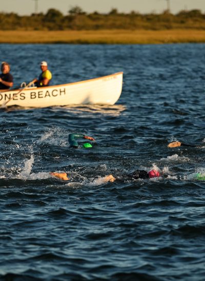 IRONMAN 70.3 New York athletes swimming at Jones Beach alongside a Jones Beach lifeguard boat.