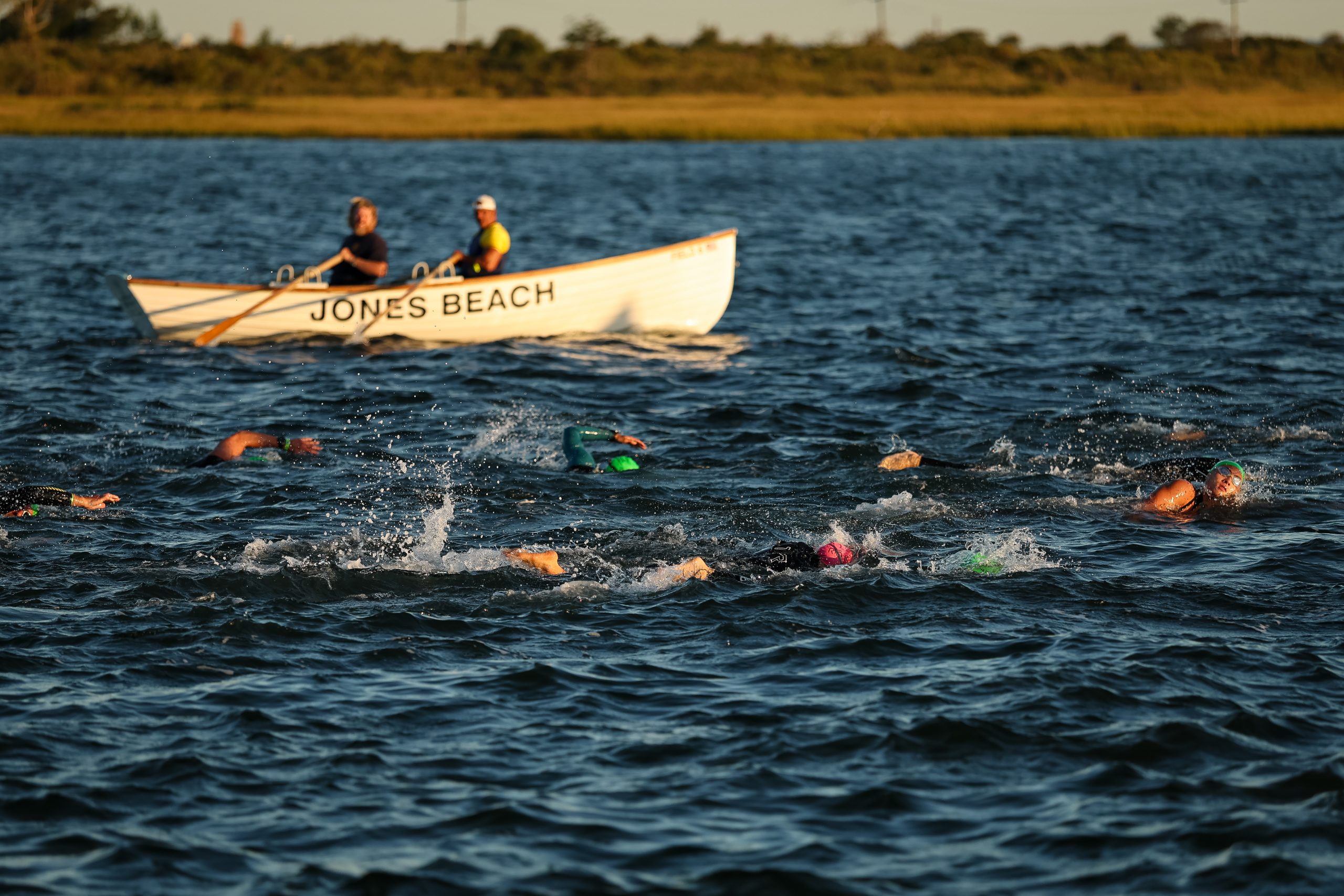 IRONMAN 70.3 New York athletes swimming at Jones Beach alongside a Jones Beach lifeguard boat.